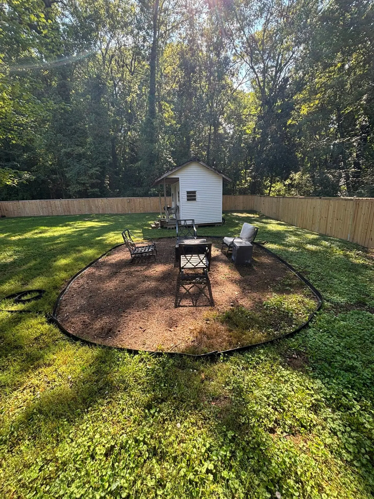Backyard seating area with edging and fresh ground cover near a shed