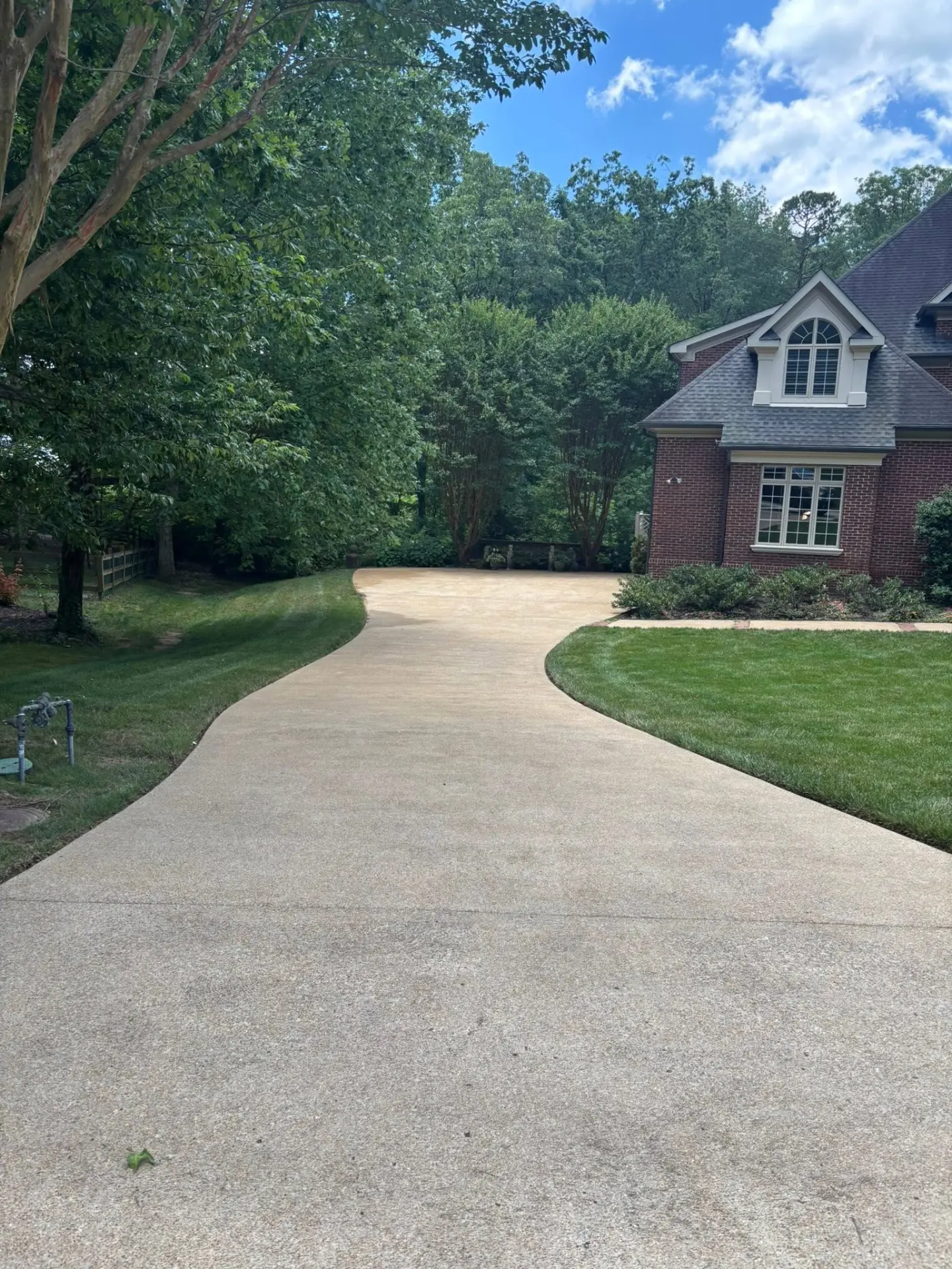 Freshly pressure washed driveway in front of a brick home