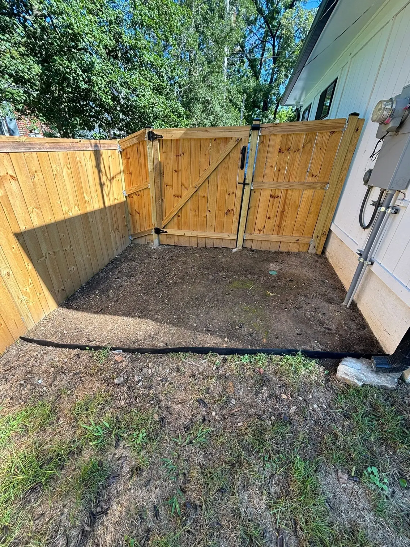 New wood privacy fence and double gate built beside a house